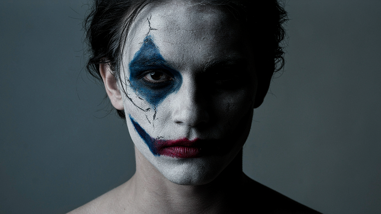 A dramatic, shadowed portrait in theatrical face paint